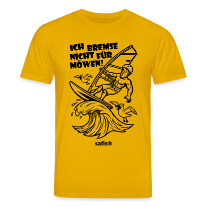 Schwarzer print vorn auf einem dunkelgelben safis® T-Shirt aus Bio-Baumwolle mit der Aufschrift 'ICH BREMSE NICHT FÜR MÖWEN!'. Die Cartoon-Grafik zeigt einen Windsurfer mit Helm auf einer Welle, umringt von fliegenden Möwen. -Möwe- Unisex Bio-T-Shirt CREATOR - Spektralgelb