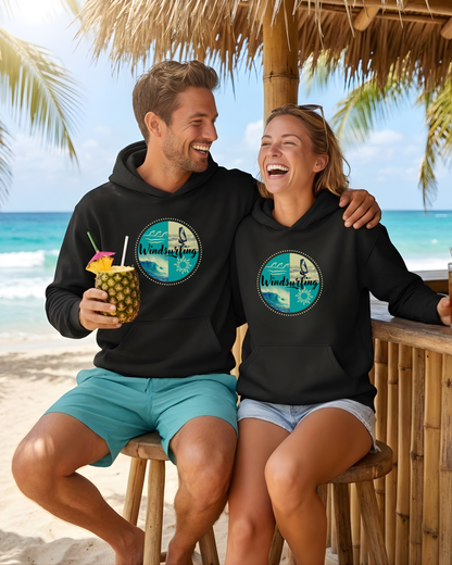 Ein junges Pärchen an einer Beachbar am Strand. Beide tragen einen schwarzen Bio-Hoodie mit einem Windsurfing-Design.